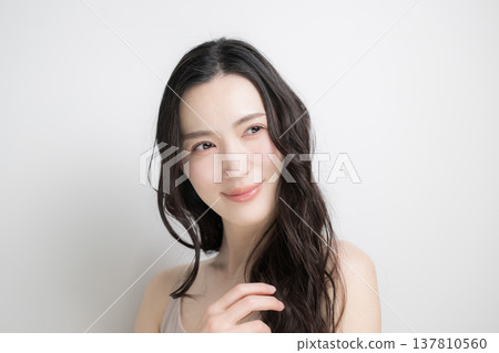 A woman with long, permed black hair flowing against a white background; an image for hair care and treatments. A woman with long, permed black hair flowing against a white background; an image for hair care and treatments. 137810560