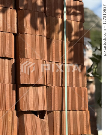 Stacked red bricks in sunlight with shadows creating a textured background Stacked red bricks in sunlight with shadows creating a textured background 137810657