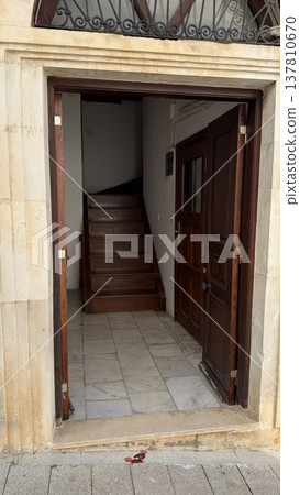 Open wooden door leading to staircase in narrow entryway of residential building 137810670