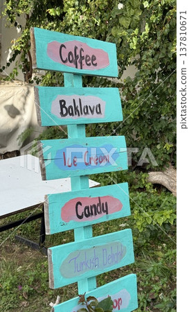 Colorful wooden signpost with dessert and beverage names in outdoor garden setting Colorful wooden signpost with dessert and beverage names in outdoor garden setting 137810671