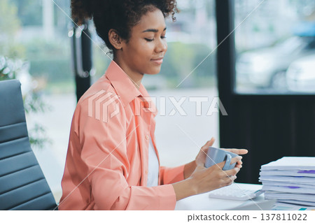 Smiling businesswoman working on laptop in office Smiling businesswoman working on laptop in office 137811022