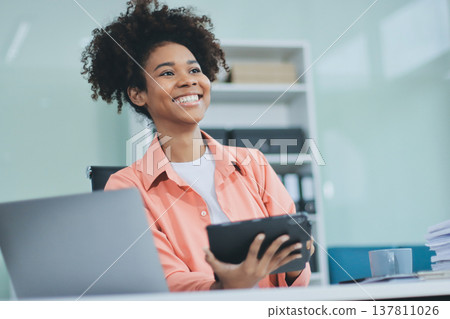 Smiling businesswoman working on laptop in office 137811026