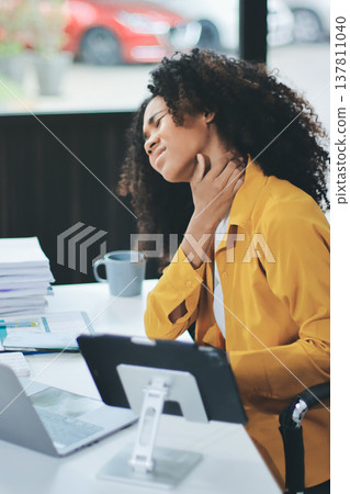 Businesswoman experiencing discomfort and pain in her lower back while sitting at her desk, working on a laptop in a modern office environment, highlighting work-related health issues and stress Businesswoman experiencing discomfort and pain in her lower back while sitting at her desk, working on a laptop in a modern office environment, highlighting work-related health issues and stress 137811040