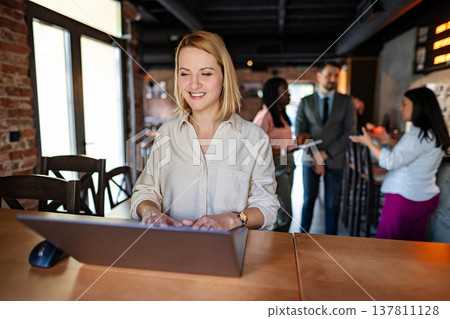 Smiling woman working on laptop in modern cafe 137811128