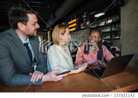Diverse business colleagues working on laptop and tablet during informal meeting 137811142
