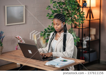 African American woman working from home using laptop computer African American woman working from home using laptop computer 137811156