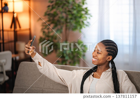 Young black woman taking selfie with smartphone at home Young black woman taking selfie with smartphone at home 137811157