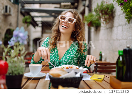 Portrait of smiling woman eating pasta at cozy italian restaurant outdoors. Tourism, food and drink Portrait of smiling woman eating pasta at cozy italian restaurant outdoors. Tourism, food and drink 137811280
