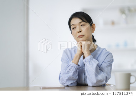 一位年近六十的女士雙手托腮,陷入沉思。 一位年近六十的女士雙手托腮,陷入沉思。 137811374