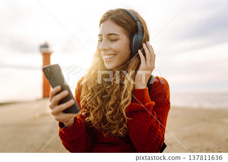 Relaxed woman enjoying music by the waterfront while wearing headphone. Travel and blogging concept 137811636