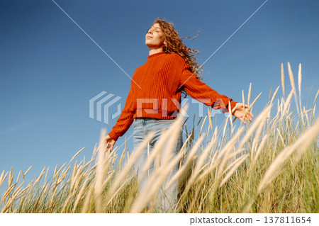 Beautiful young woman enjoying nature outdoors in tall grass. Flying hairs. Lifestyle. Fashion style Beautiful young woman enjoying nature outdoors in tall grass. Flying hairs. Lifestyle. Fashion style 137811654