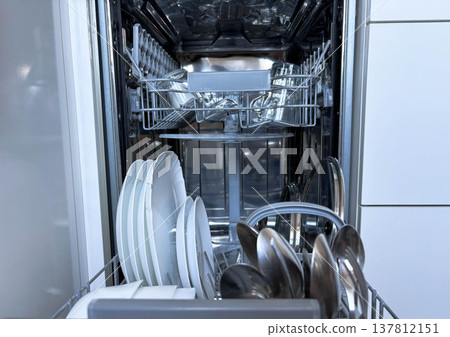 Open dishwasher with clean dishes. Clean dishes and cutlery after a dishwasher cycle 137812151