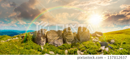 sunset over mountainous panorama with huge stones near hillside. beautiful summer landscape on cloudy weather. alpine scenery with green grassy meadow. scenic outdoor environment under rainbow sunset over mountainous panorama with huge stones near hillside. beautiful summer landscape on cloudy weather. alpine scenery with green grassy meadow. scenic outdoor environment under rainbow 137812637