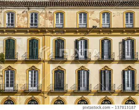 Sunlit Yellow Historic Facade With Shuttered Windows and Wrought Iron Balconies, Mediterranean Style Sunlit Yellow Historic Facade With Shuttered Windows and Wrought Iron Balconies, Mediterranean Style 137813187