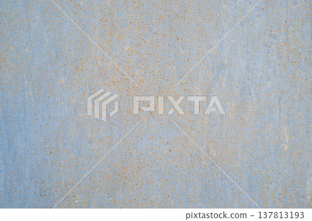 A horizontal close-up shot of a light blue painted metal surface covered with a dense pattern of tiny orange rust spots. A horizontal close-up shot of a light blue painted metal surface covered with a dense pattern of tiny orange rust spots. 137813193