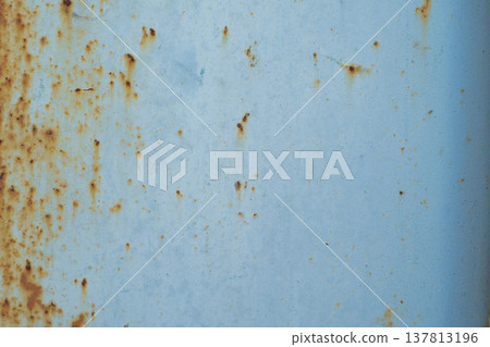 A horizontal close-up of a weathered light blue metal surface covered with multiple small orange rust spots and corrosion. 137813196