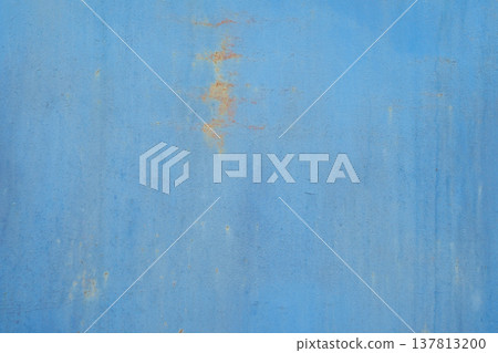 A horizontal close-up of a flat blue painted metal surface showing subtle texture, faint scratches, and small spots of orange rust. A horizontal close-up of a flat blue painted metal surface showing subtle texture, faint scratches, and small spots of orange rust. 137813200