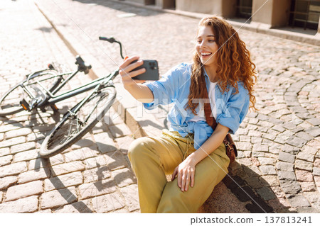 Young woman with bike outdoors in park in summer day using mobile phone. Travel, relax and lifestyle 137813241