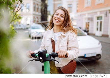 Beautiful woman riding an electric scooter. Street-style, Ecological transport. Active lifestyle. 137813242
