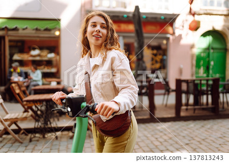 Beautiful woman riding an electric scooter. Street-style, Ecological transport. Active lifestyle. 137813243
