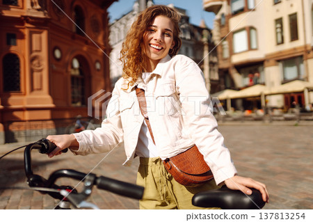 Lovely young woman posing with bike on street of city, on sunny day. Active lifestyle. Eco transport 137813254