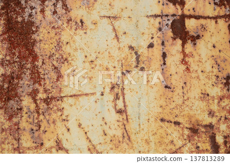 A horizontal close-up shot of a heavily weathered metal surface with deep rust, scratches, and remains of yellowish paint. 137813289