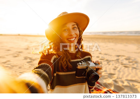 Pretty woman with a professional photographer taking selfie on the beach at sunset. Travel blog. 137813373