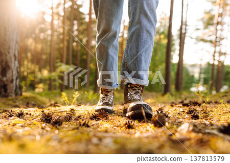 Hiker's boots stepping on a blanket of fallen autumnal orange leaves in the forest. Travel Hiker's boots stepping on a blanket of fallen autumnal orange leaves in the forest. Travel 137813579