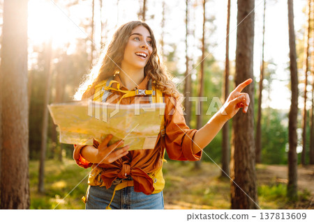 Young woman holding map in forest. Relaxed woman hiker looking navigation searching route. Young woman holding map in forest. Relaxed woman hiker looking navigation searching route. 137813609