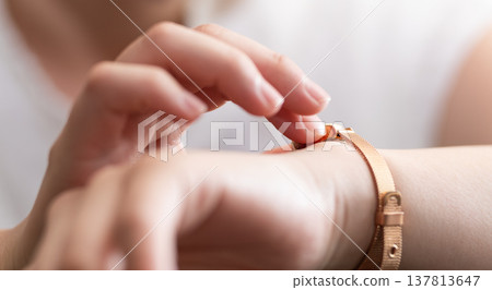 一位女士正在調整手錶。 137813647