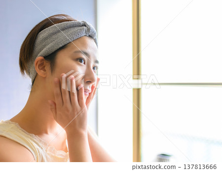 A woman doing skin care after washing her face A woman doing skin care after washing her face 137813666