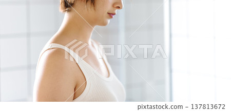 From the shoulders up of a woman facing sideways at the sink. From the shoulders up of a woman facing sideways at the sink. 137813672