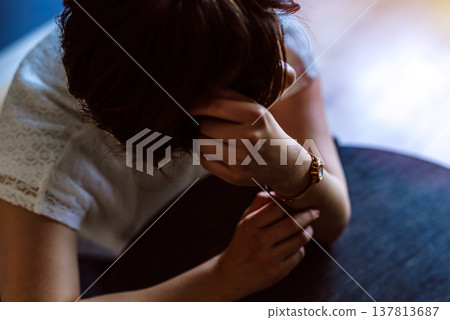 一位女士神情憂鬱，面朝下躺在桌上。 137813687