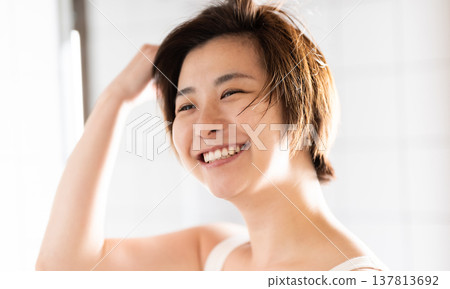 一位微笑的女士正用手指梳理著頭髮。 137813692