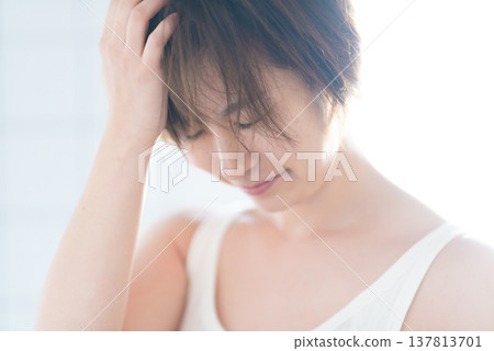 The gentle expression on the woman's face as she touches her hair. The gentle expression on the woman's face as she touches her hair. 137813701