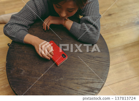 A red smartphone and a woman's hand on the desk. A red smartphone and a woman's hand on the desk. 137813724