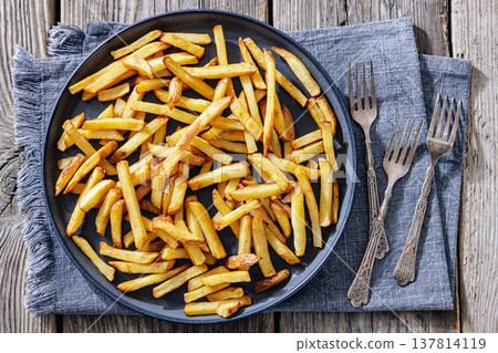 Crispy french fries on a plate with forks 137814119