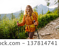Young woman traveler hiking poles on trail among the mountains. Hiking. Active lifestyle. 137814741