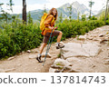Young woman traveler hiking poles on trail among the mountains. Hiking. Active lifestyle. 137814743