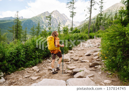 Young woman traveler hiking poles on trail among the mountains. Hiking. Active lifestyle. 137814745