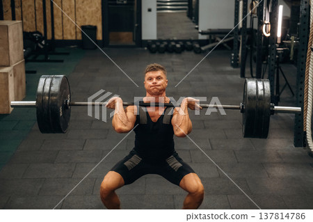 Strong arms and back. Athletic man performing weightlifting exercises with a barbell in a gym Strong arms and back. Athletic man performing weightlifting exercises with a barbell in a gym 137814786
