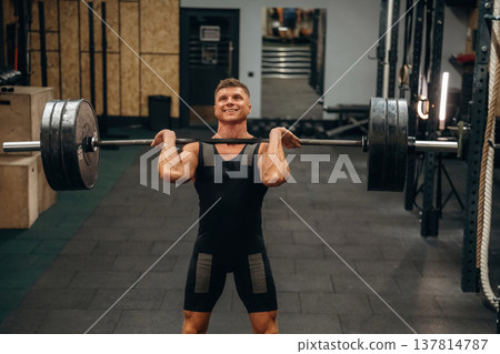 Strong arms and back. Athletic man performing weightlifting exercises with a barbell in a gym Strong arms and back. Athletic man performing weightlifting exercises with a barbell in a gym 137814787