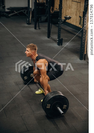 Professional occupation. Athletic man performing weightlifting exercises with a barbell in a gym 137814796