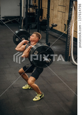 Professional occupation. Athletic man performing weightlifting exercises with a barbell in a gym 137814798