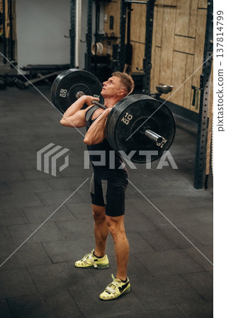 Professional occupation. Athletic man performing weightlifting exercises with a barbell in a gym Professional occupation. Athletic man performing weightlifting exercises with a barbell in a gym 137814799