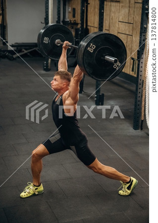 Hands are full high up. Athletic man performing weightlifting exercises with a barbell in a gym 137814800