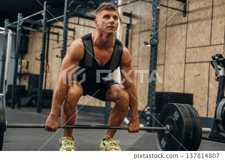 Ready for lifting. Athletic man performing weightlifting exercises with a barbell in a gym Ready for lifting. Athletic man performing weightlifting exercises with a barbell in a gym 137814807