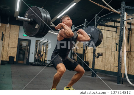 Conception of weightlifting. Athletic man is doing exercise with a barbell in a gym Conception of weightlifting. Athletic man is doing exercise with a barbell in a gym 137814812
