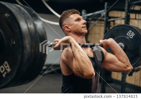 Conception of weightlifting. Athletic man is doing exercise with a barbell in a gym Conception of weightlifting. Athletic man is doing exercise with a barbell in a gym 137814815