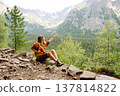 Young traveler woman with a yellow backpack on a cliff. Sports concept, traveler. Active lifestyle. 137814822